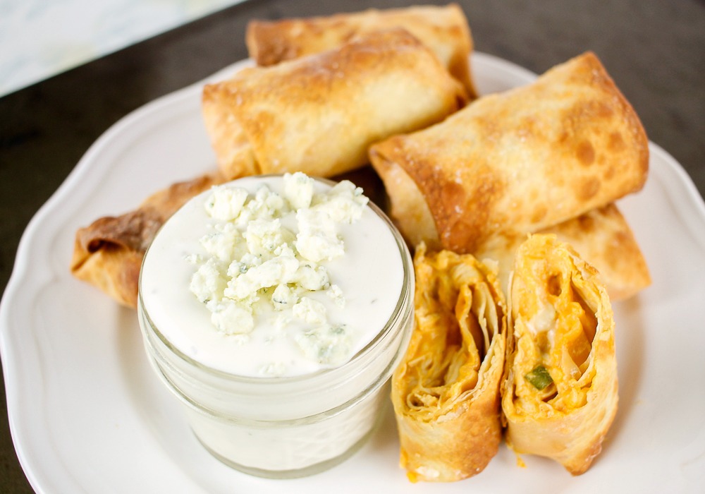 a white plate with buffalo chicken egg rolls and blue cheese dressing