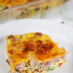 slice of keto breakfast casserole with ham, eggs, vegetables and cheese on a white plate