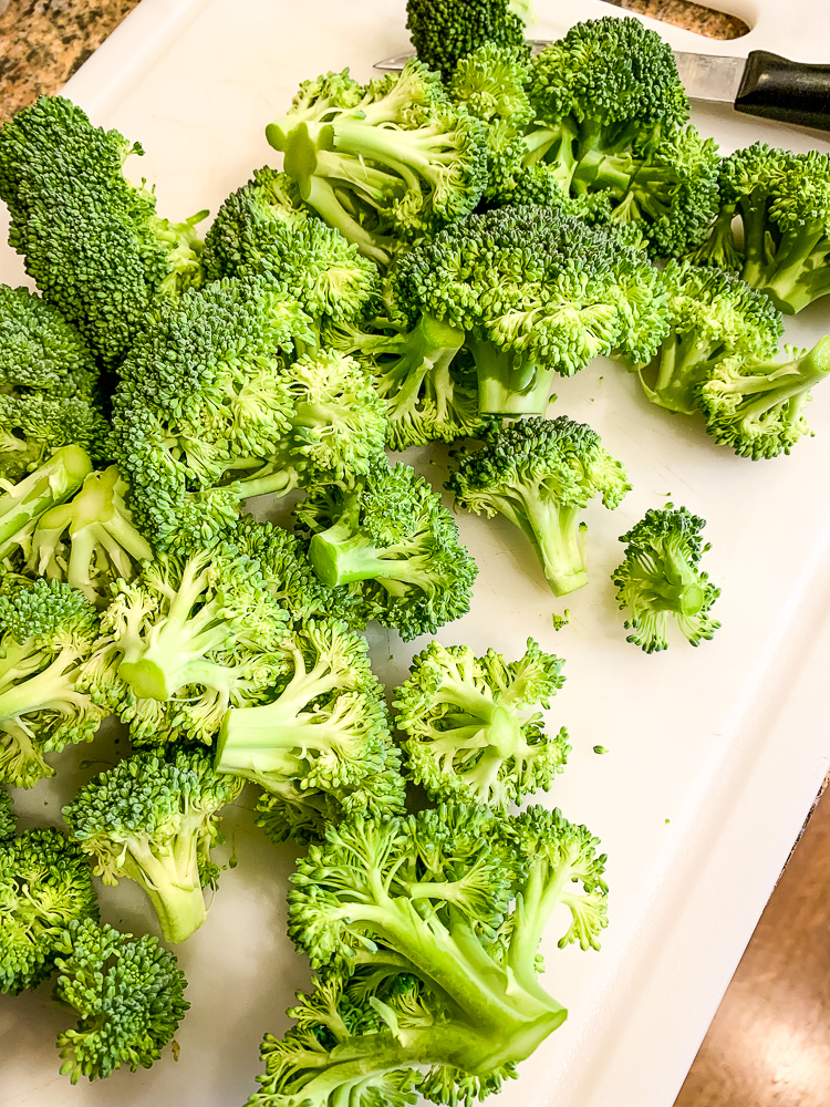 white cutting board with raw broccoli florets