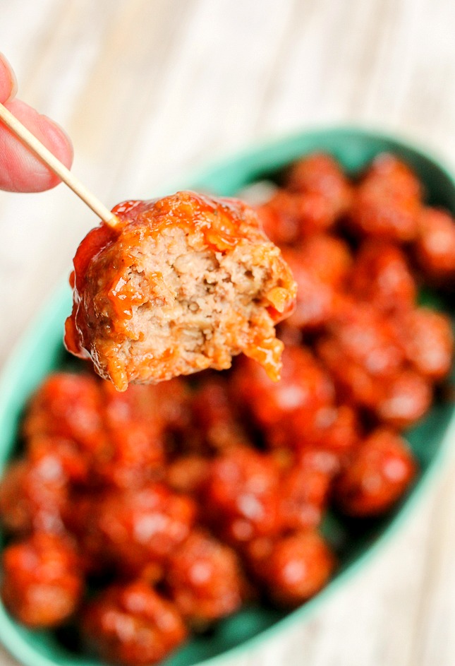 a BBQ meatball on a toothpick that has a bite taken out of it