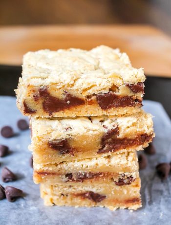 a stack of 3 Chocolate Chip Blonde Brownies with chocolate chips scattered around the pile