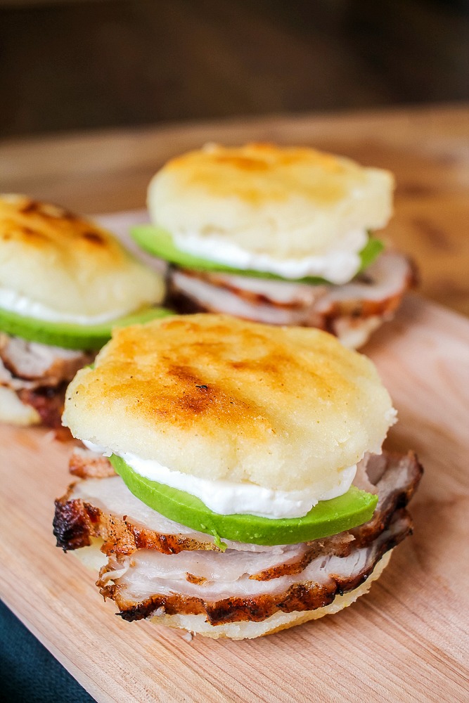 Venezuelan arepa sandwich filled with grilled pork, avocados and sour cream