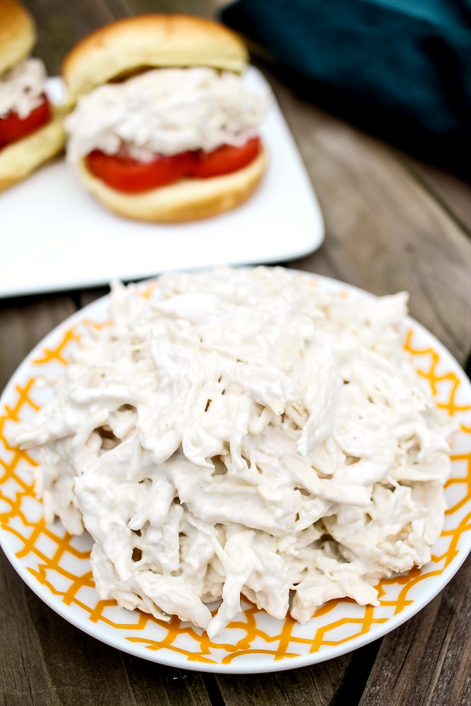 a plate of simple chicken salad with two chicken salad sandwiches in the background