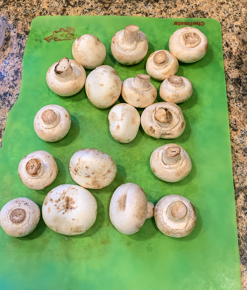 green cutting board with washed mushrooms