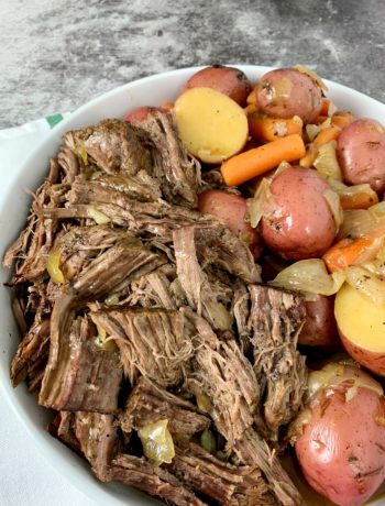 a white round platter with shredded beef, potatoes and carrots