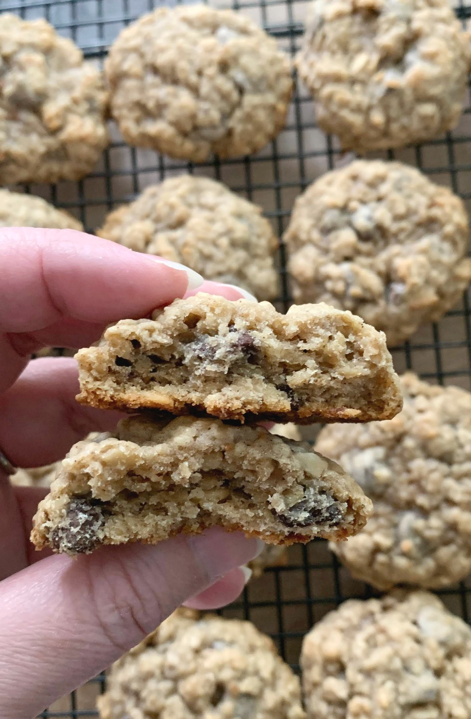 a hand holding a banana oatmeal chocolate chip cookie that's broken in half