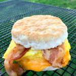a cooling rack with a bacon, egg and cheese biscuit sandwich on top of it
