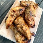 wooden cutting board with grilled chicken breasts piled on top