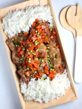 a rectangle dish with white rice on either end and Jamaican Brown Stew Chicken in the middle