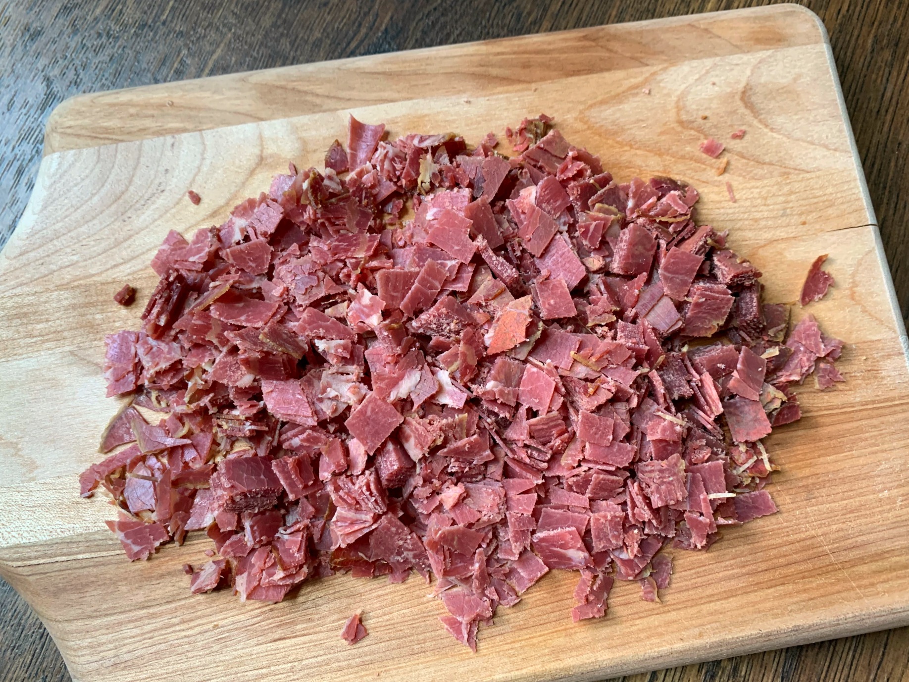 cutting board with chopped chipped beef in a pile