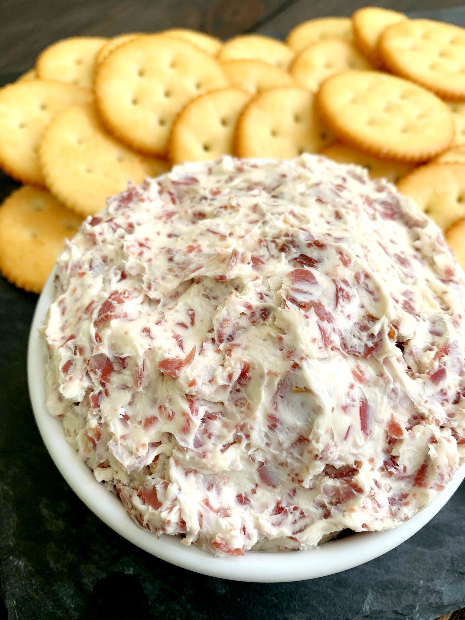 white bowl with chipped beef dip with crackers in the background