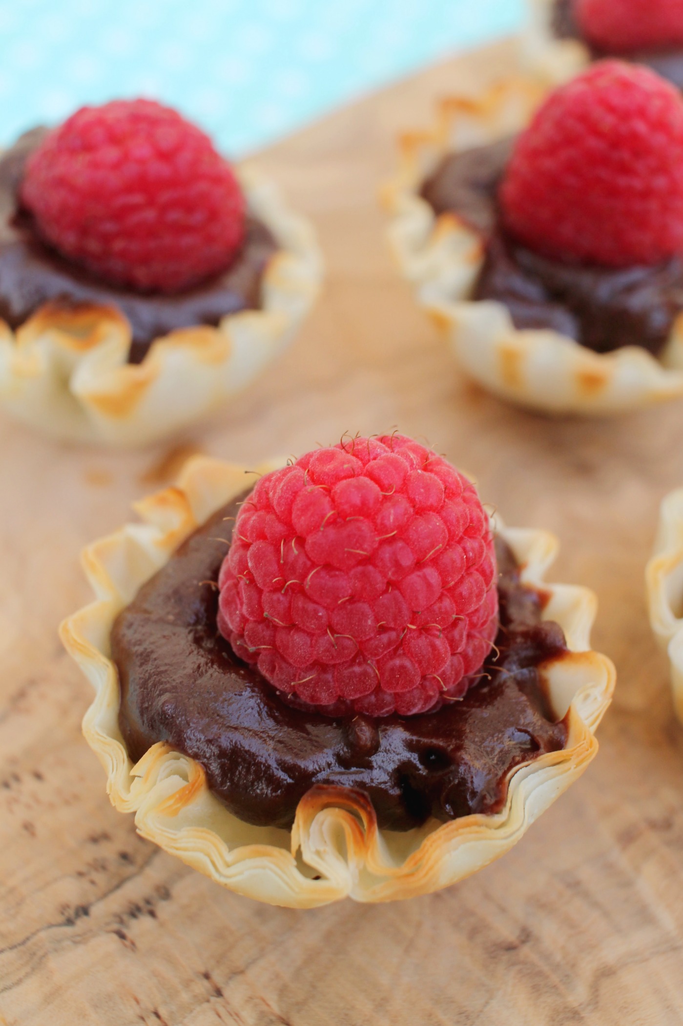 up close shot of a phyllo tart shell filled with chooclate ganache and topped with a raspberry