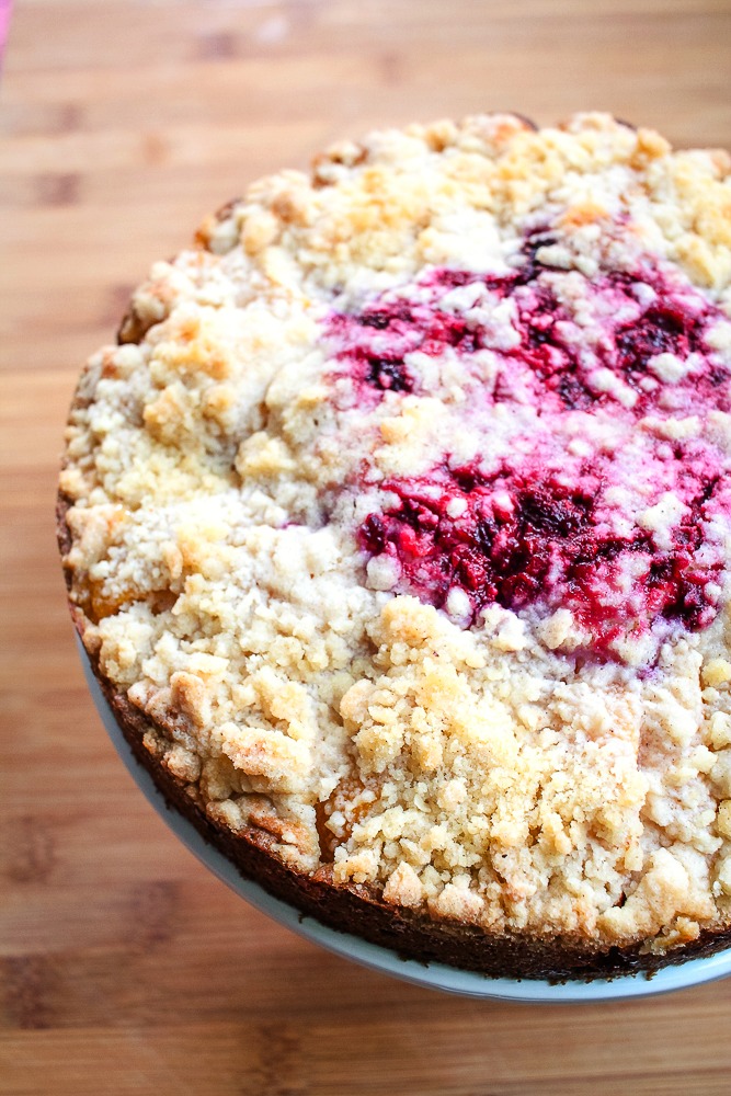 round coffee cake with crumb topping and raspberries in the center