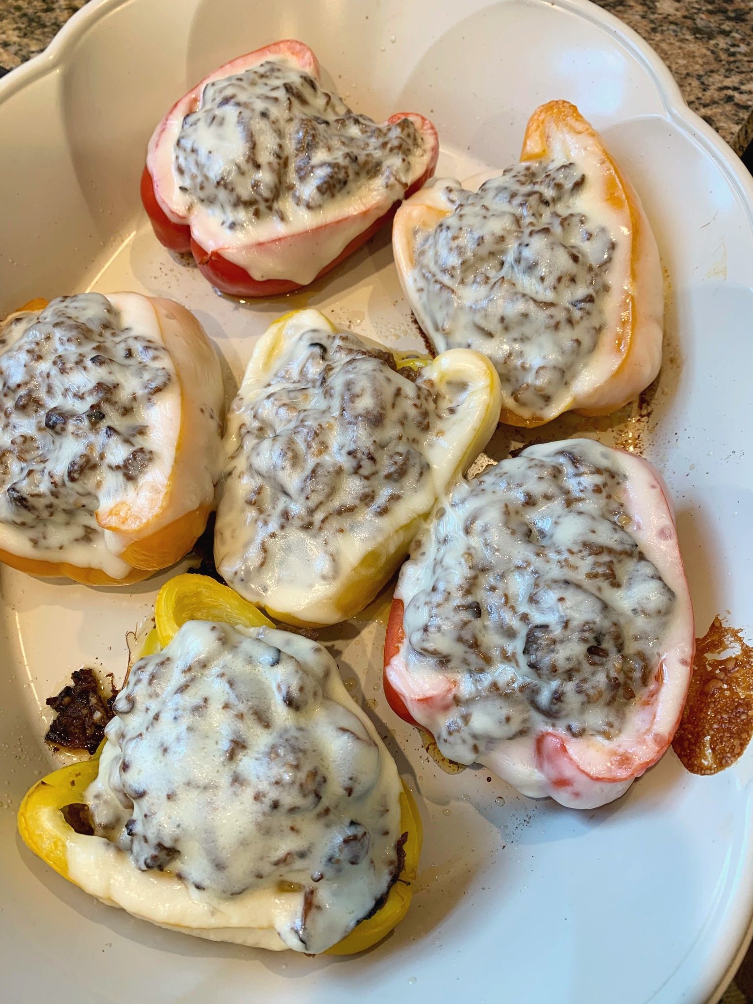 a white pan filled with 6 Philly cheese steak stuffed peppers topped with melted cheese