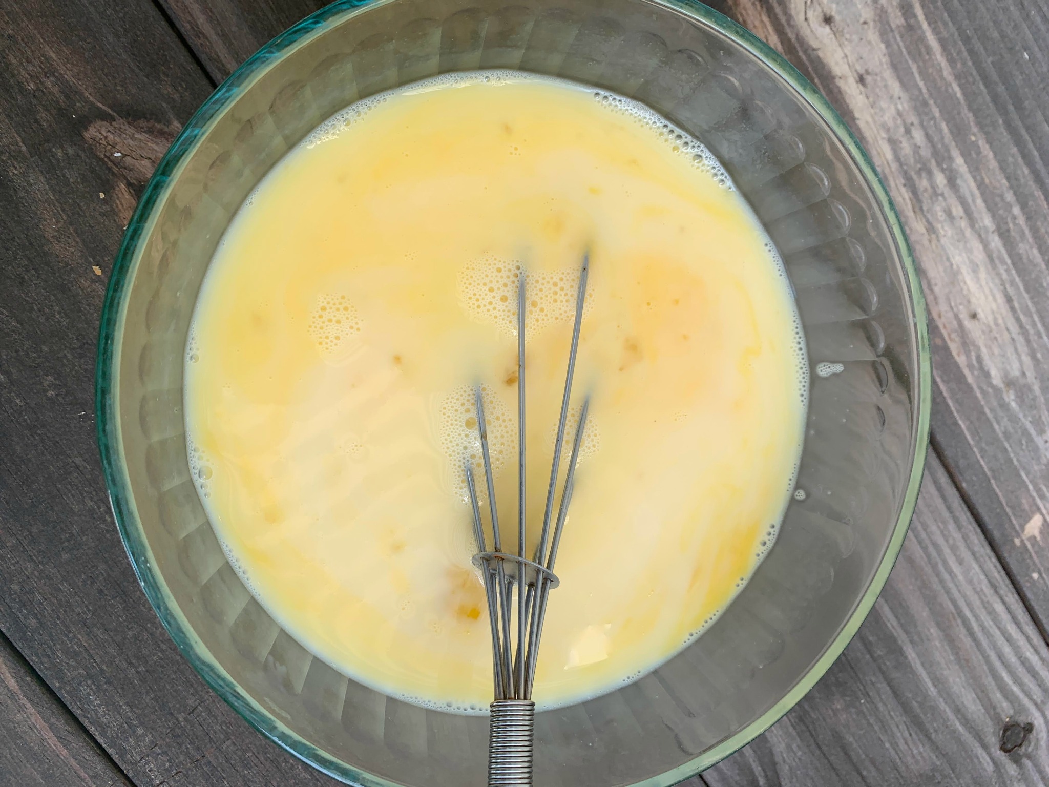 glass bowl with egg custard and a whisk