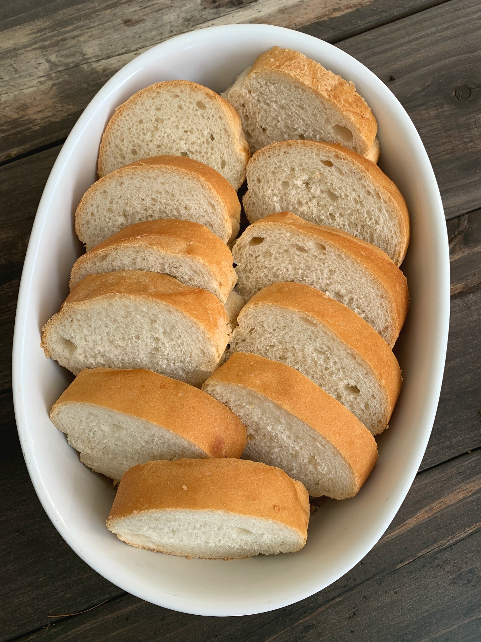 white oval baking dish with bread slices lined up