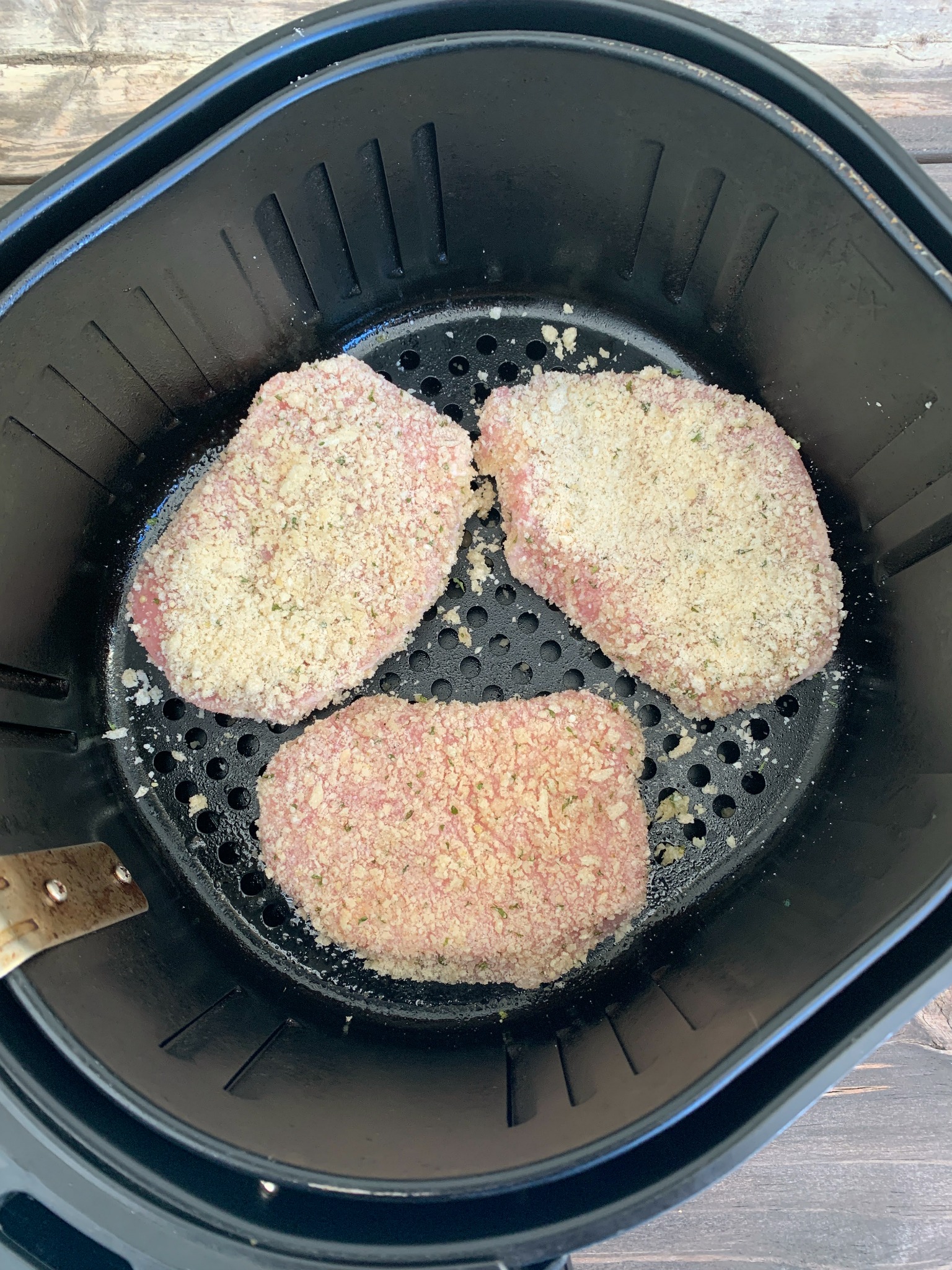 3 uncooked pork chops in the air fryer basket