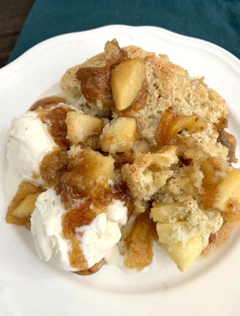 a serving of apple pudding cake on a white plate with two scoops of vanilla ice cream