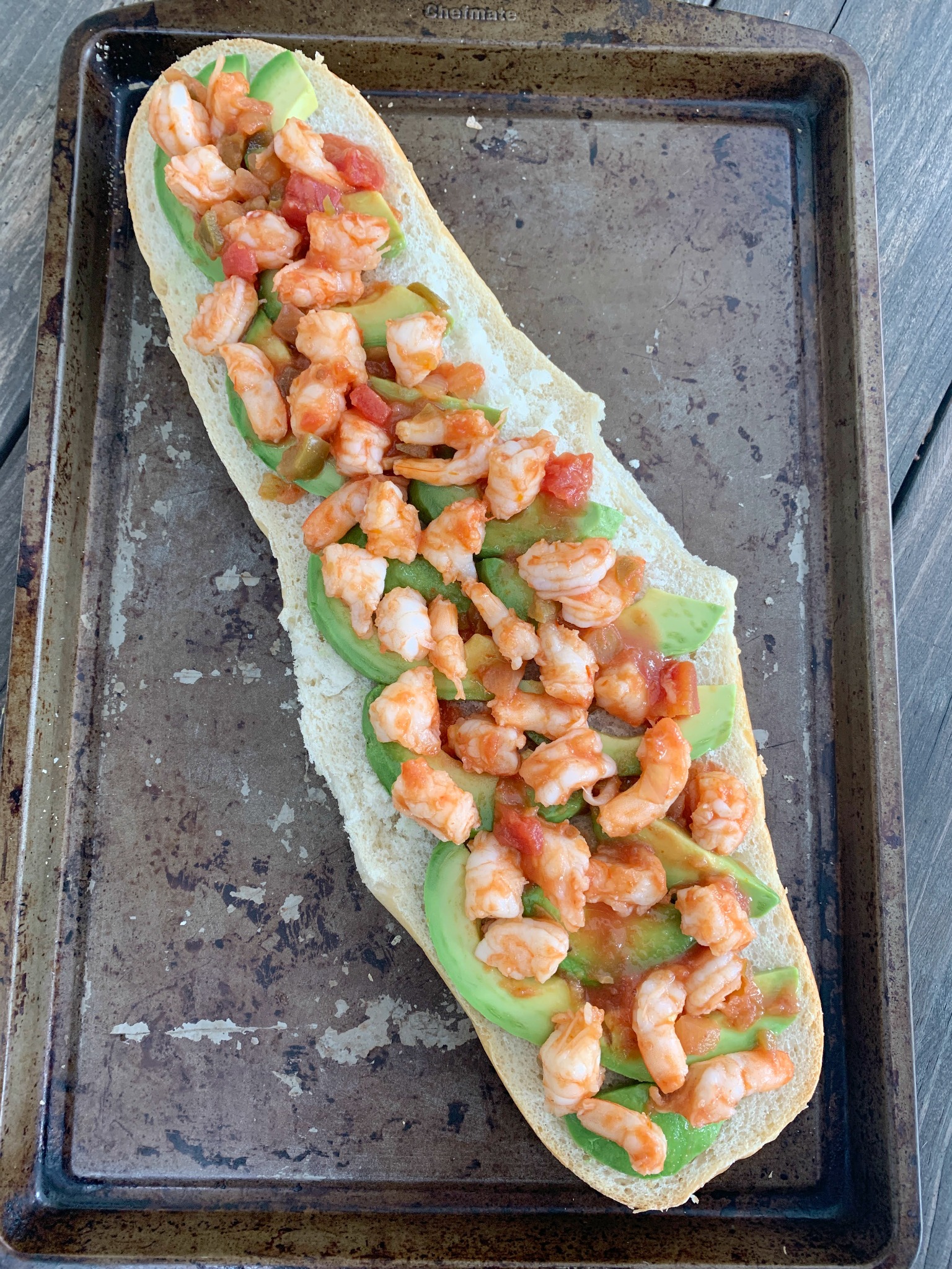 half a loaf of french bread with avocado slices and chopped shrimp