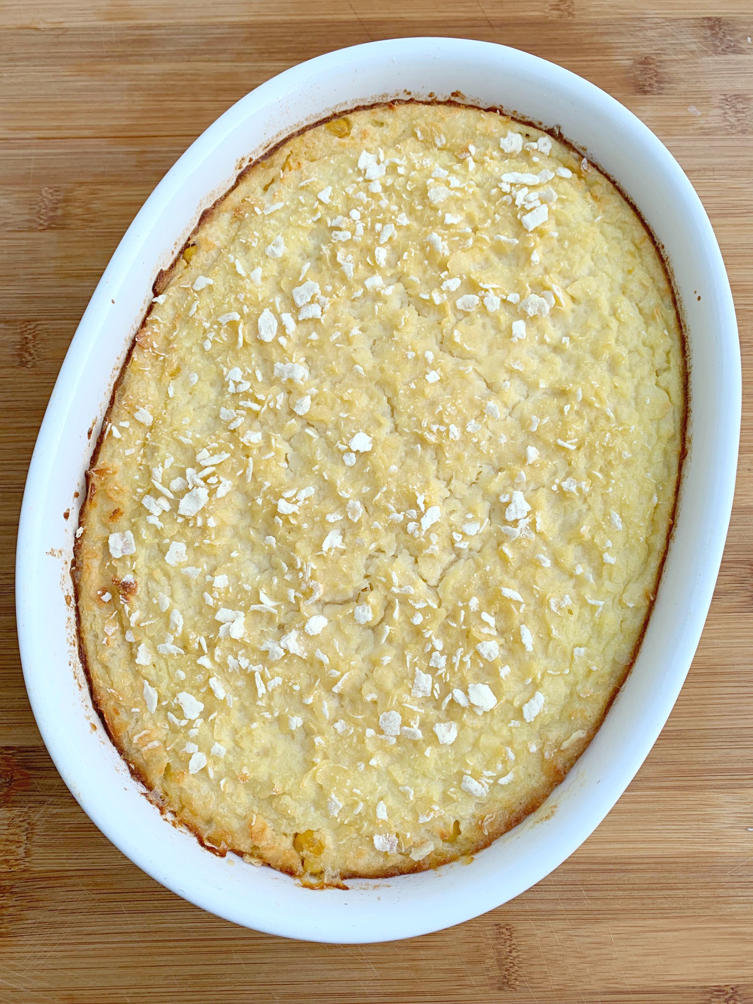 a white oval dish with baked scalloped corn