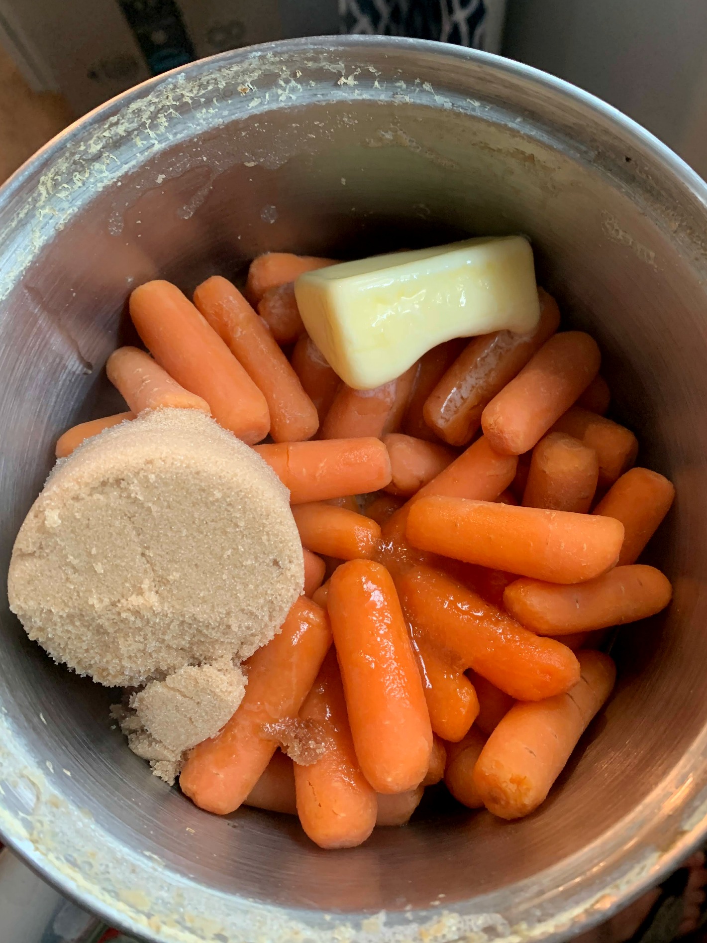 sauce pan with baby carrots a scoop of brown sugar and half a stick of butter