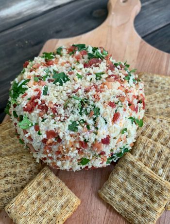 jalapeno cheese ball on a wooden cutting board with crackers around it