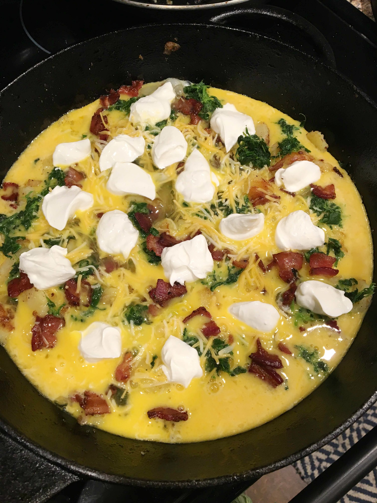 cast iron pan with a uncooked spinach and potato frittata