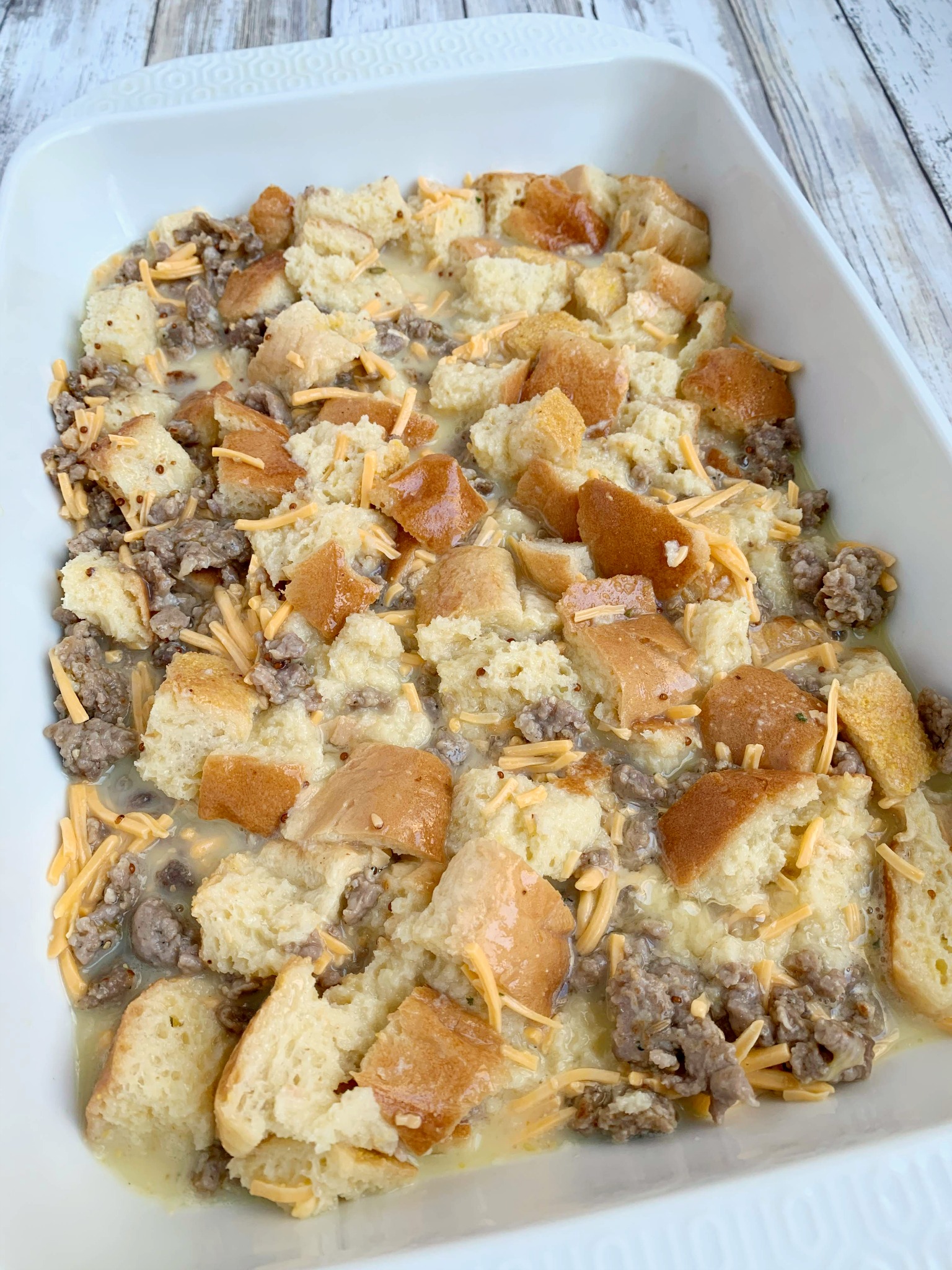 a white 13x9 pan with unbaked sausage strata