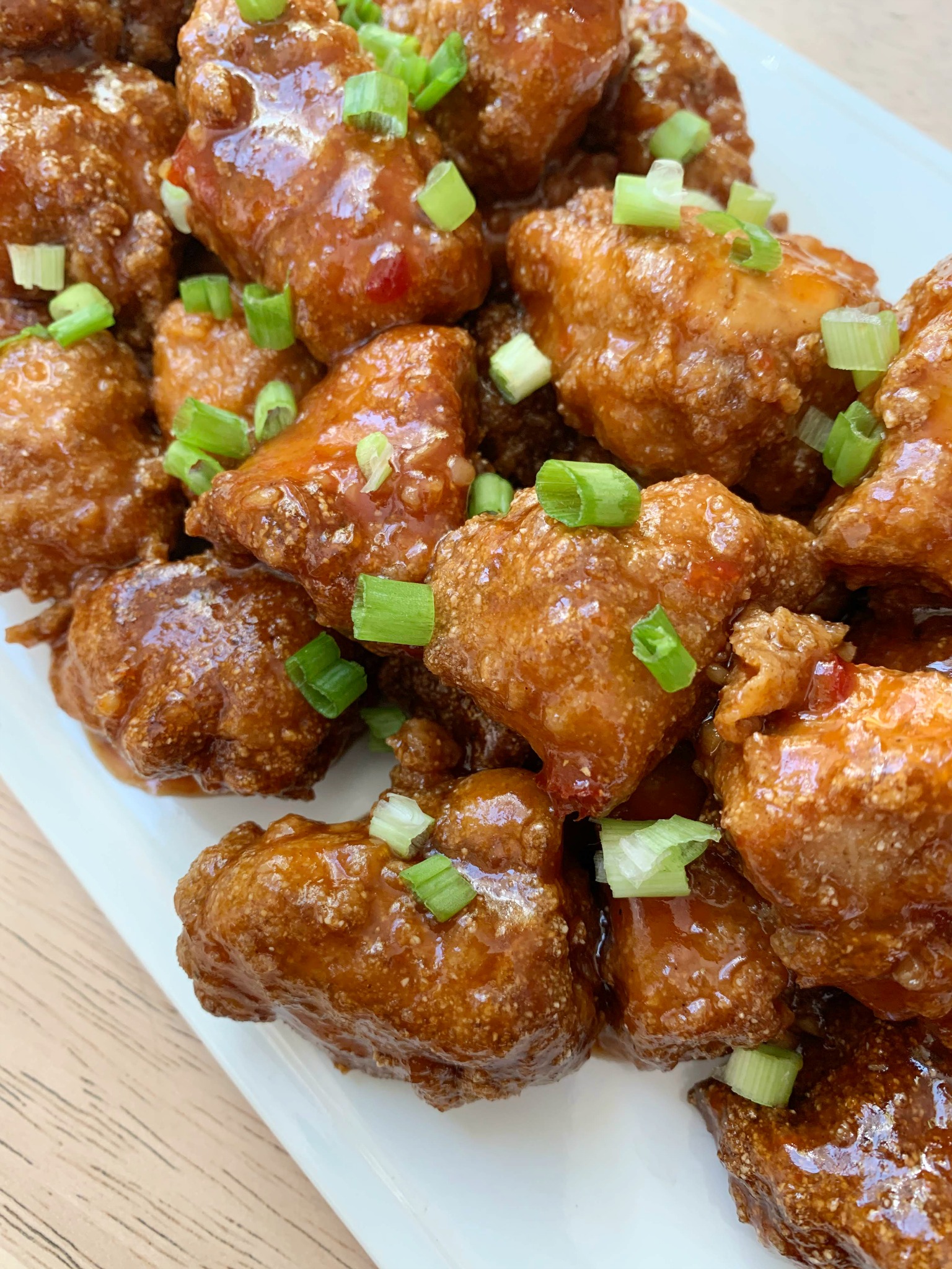 Sweet Chili Chicken on a white platter with chopped green onions