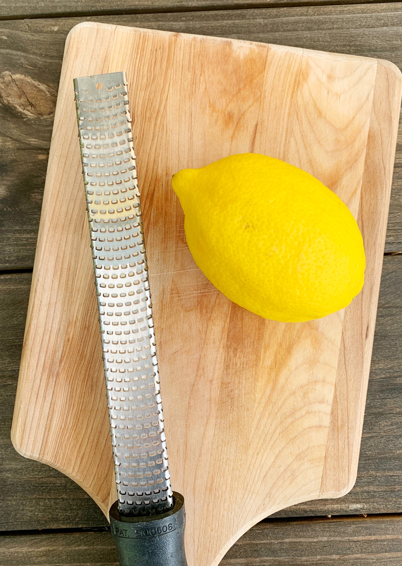 a whole lemon and a zester on a wooden cutting board