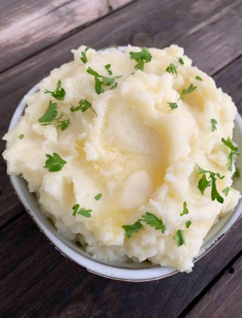 mashed potatoes in a bowl with melted butter and chopped parsley on top
