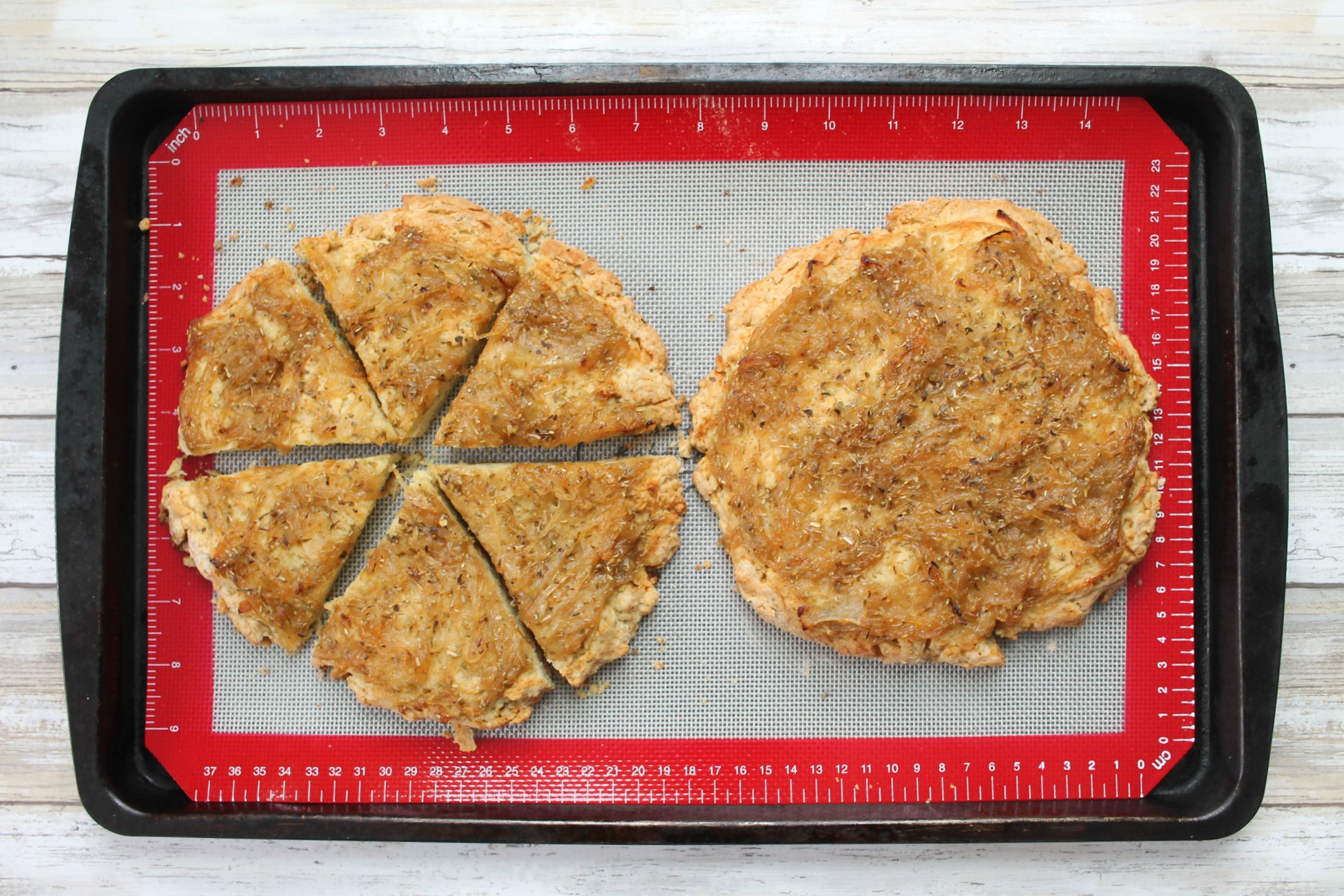 two cooked scone rounds on a cookie sheet with one cut into wedges and one whole