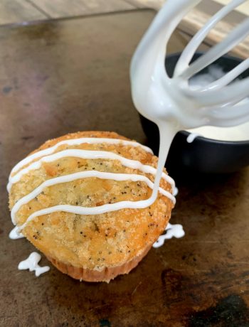 a whisk drizzling glaze on a lemon muffin